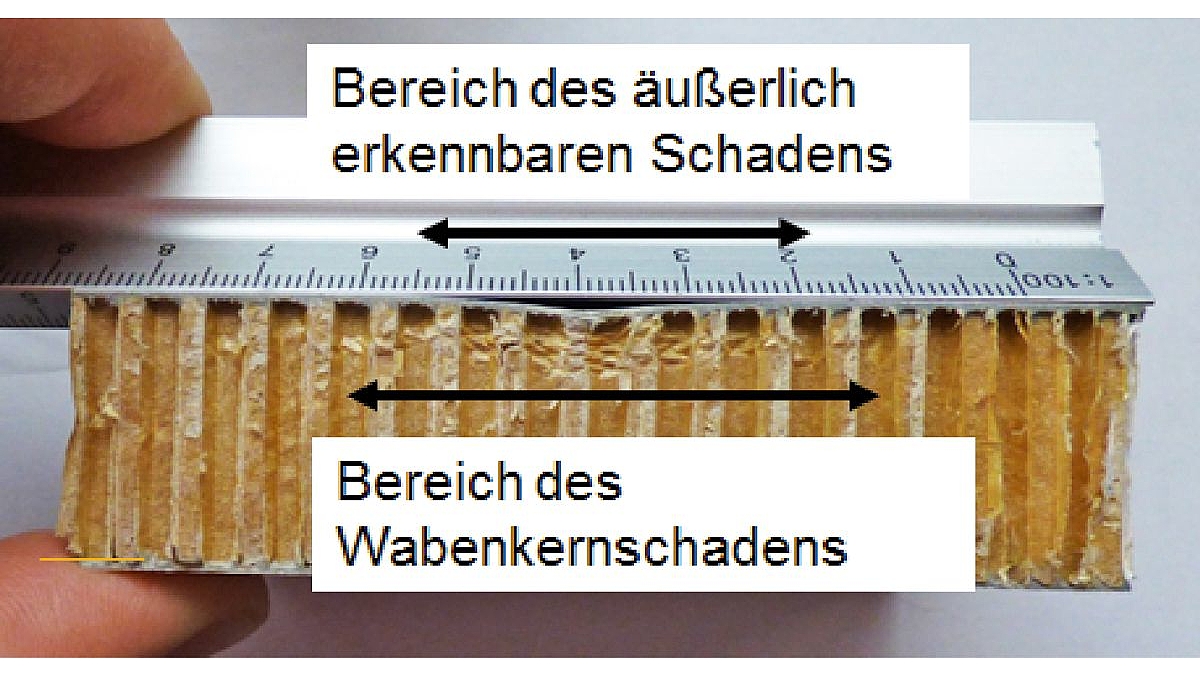 Mit einem Lineal werden an einem Bauteil der äußerlich erkennbare Schaden und der Bereich des Wabenkernschadens gemessen