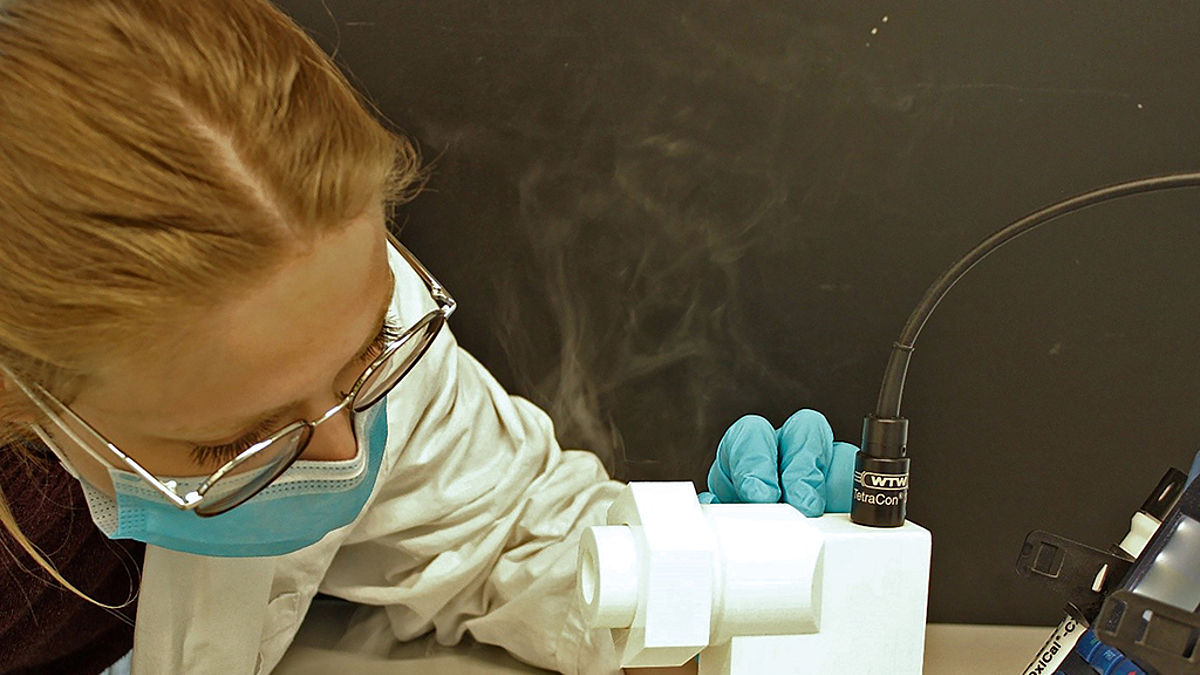 Eine Wissenschaftlerin in Schutzausrüstung während der Maskenprüfung mittels Natriumchlorid-Aerosolen
