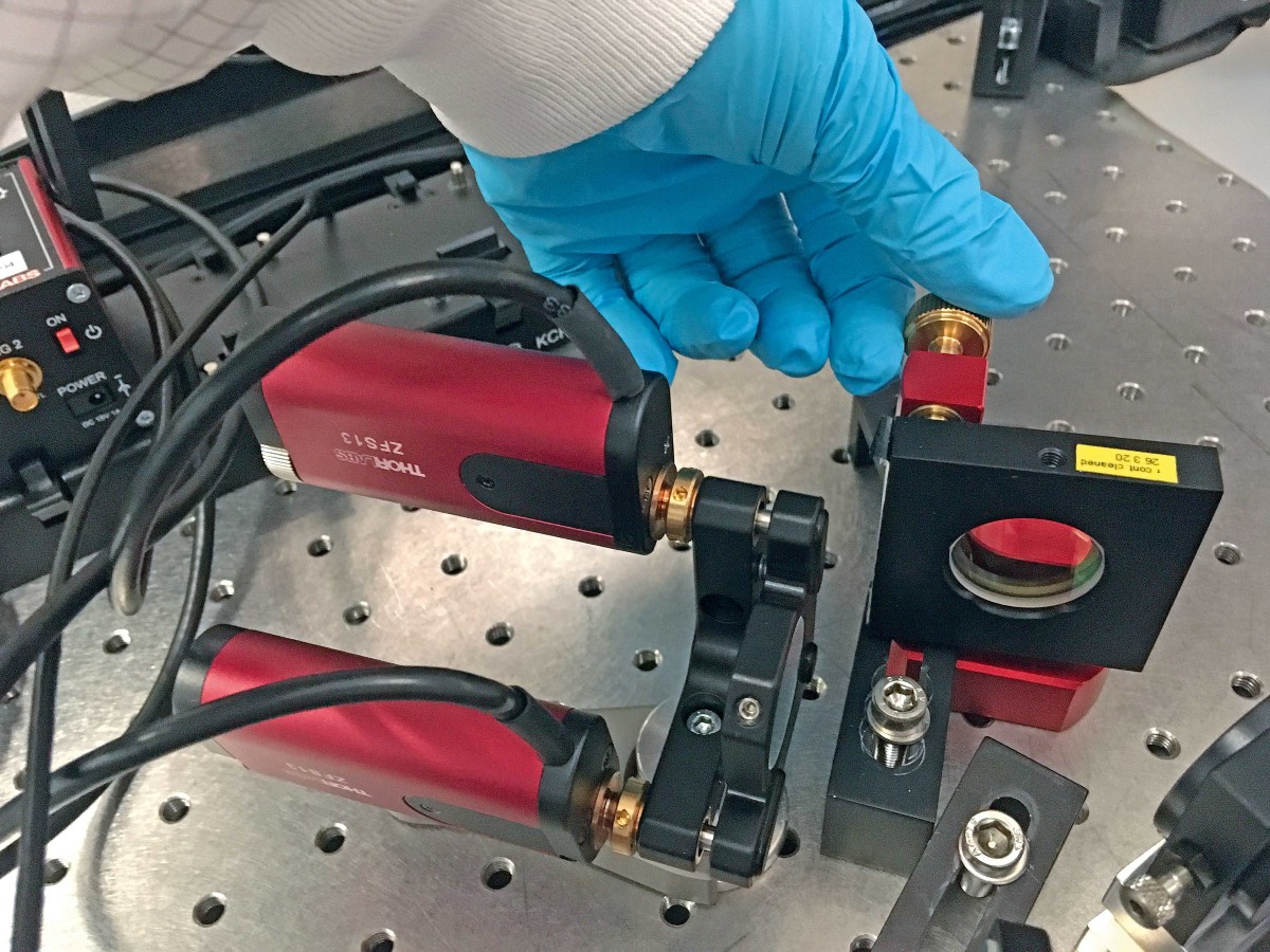 Eine Hand im Schutzhandschuh dreht an einer Schraube. An den Schrauben daneben sind Motoren angebracht.