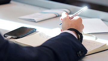 Arm eines Menschen, der Papiere bearbeitet. 